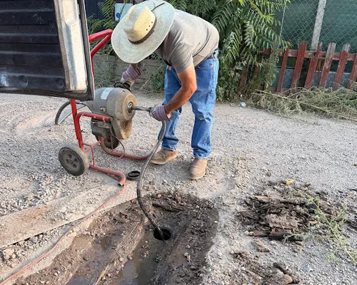 Technician clearing a clogged drain outdoors